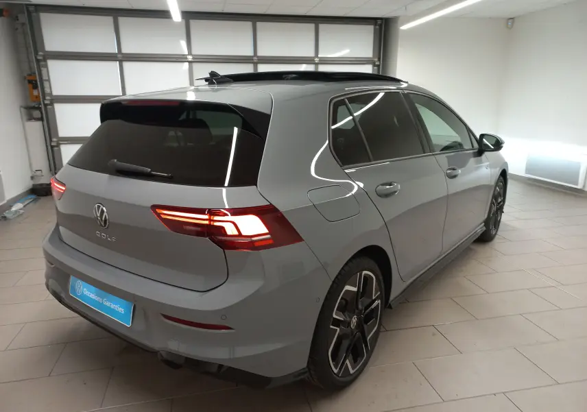Vue 3/4 arrière droite d'une Volkswagen Golf 2.0 TDI R-Line gris lunaire avec toit ouvrant panoramique en intérieur.