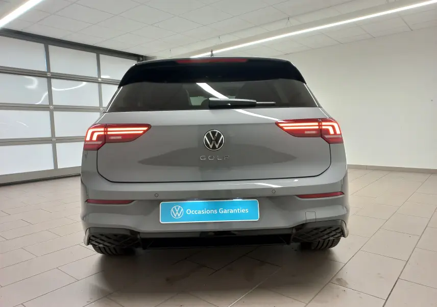Vue arrière d'une Volkswagen Golf 2.0 TDI 150 DSG7 R-Line gris lunaire avec feux LED allumés dans un garage.