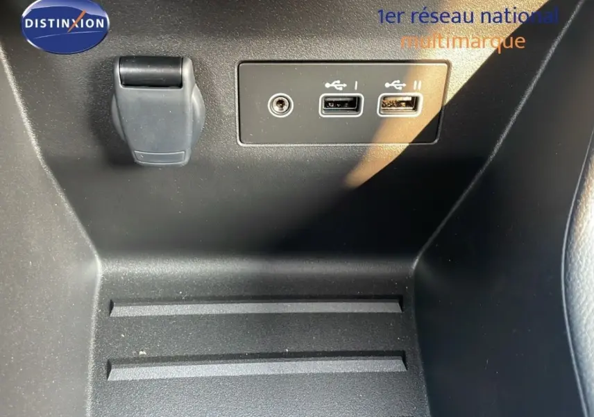Gros plan sur la console centrale noire de la Renault Clio avec deux ports USB et une prise 12V.