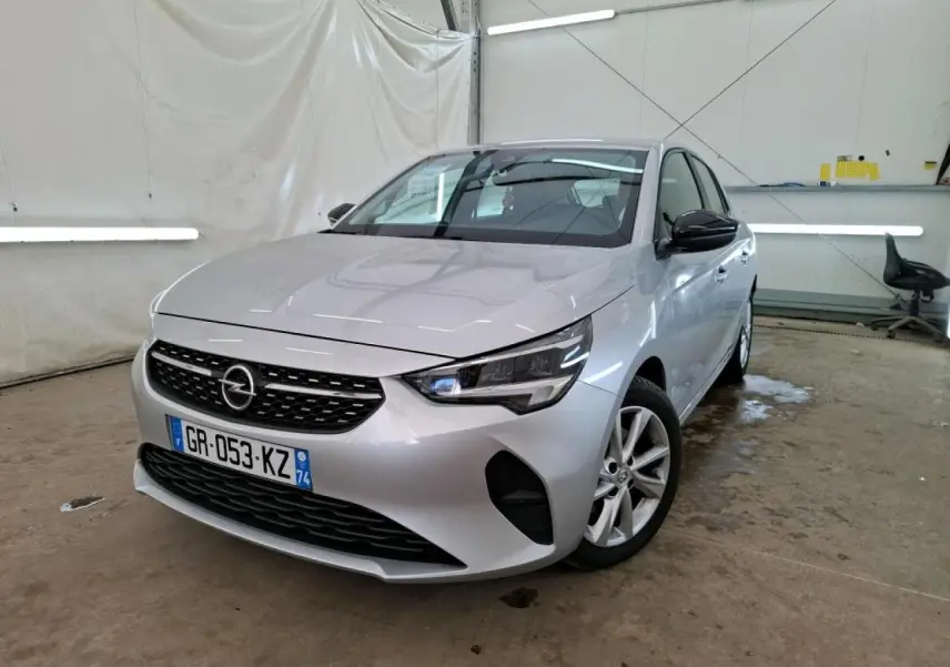 Opel Corsa gris clair vue 3/4 avant droit, avec jantes alliage 16'' et rétroviseurs noirs dans un garage.