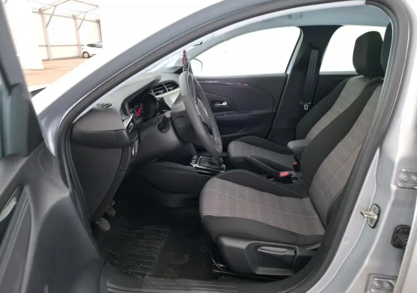 Vue intérieure côté conducteur de l’Opel Corsa gris clair 2023, avec sellerie tissu bicolore et tableau de bord moderne.