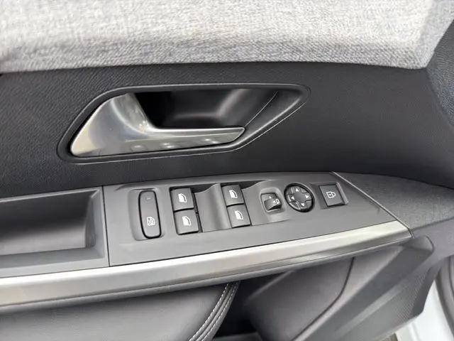 Gros plan sur la commande des vitres et la poignée intérieure côté gauche, avec finition noire et insert argenté du Peugeot 5008 blanc.
