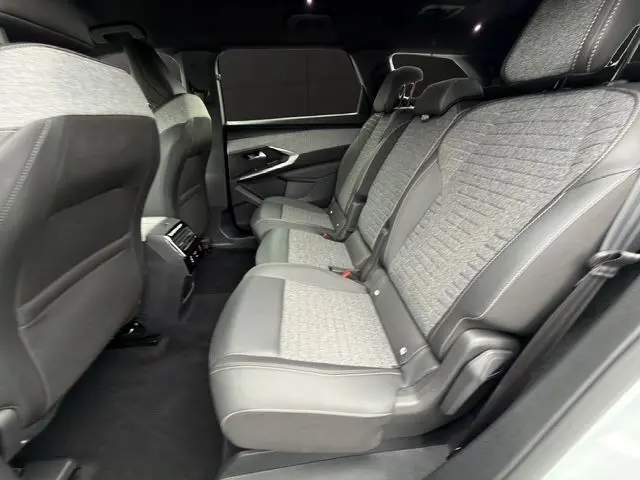 Vue latérale droite de la banquette arrière grise et noire du Peugeot 5008 Allure Hybrid 2025 avec sellerie tissu et cuir.