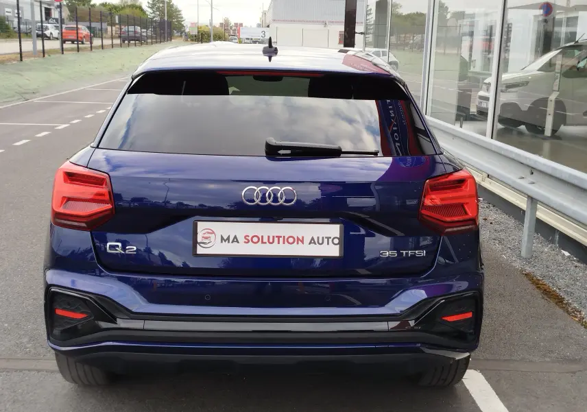 Vue arrière d'un Audi Q2 bleu Navarre 35 TFSI 2023 avec feux LED et logo Audi bien visibles.