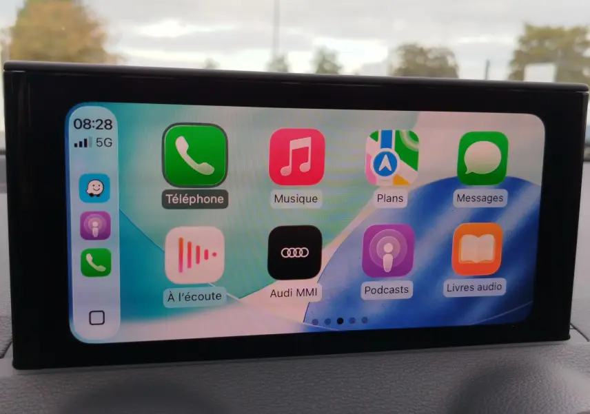Écran tactile intérieur de l'Audi Q2 2023 affichant les applications Apple CarPlay avec fond bleu et blanc.