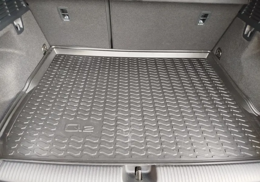 Vue intérieure du coffre de l'Audi Q2 avec tapis de protection noir marqué Q2, sans couleur extérieure visible.