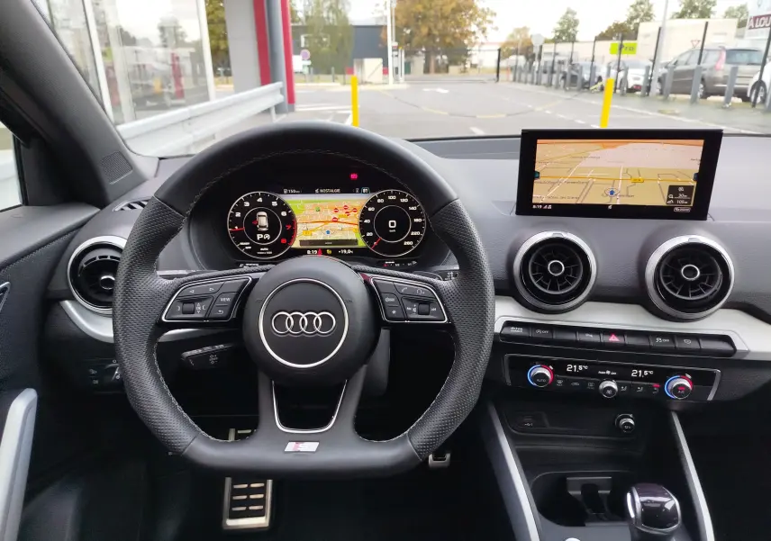 Vue intérieure centrée sur le volant multifonction et le tableau de bord numérique de l'Audi Q2 2023.
