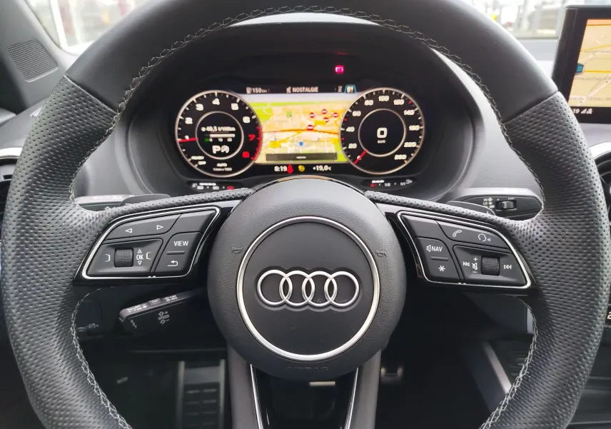 Vue rapprochée du volant perforé noir de l'Audi Q2 2023 avec affichage numérique et commandes intégrées.