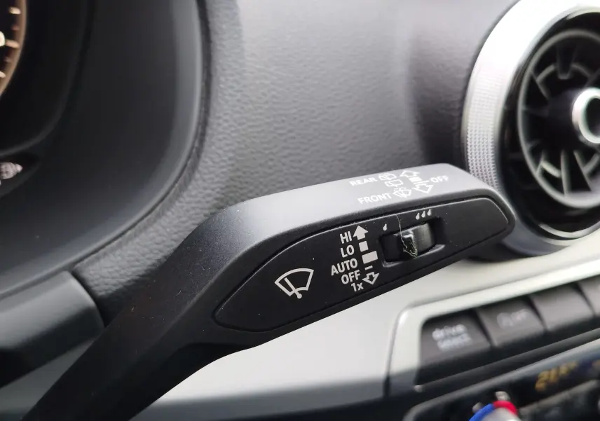 Gros plan sur la commande des essuie-glaces à gauche du volant dans l’Audi Q2 35 TFSI bleu Navarre de 2023.