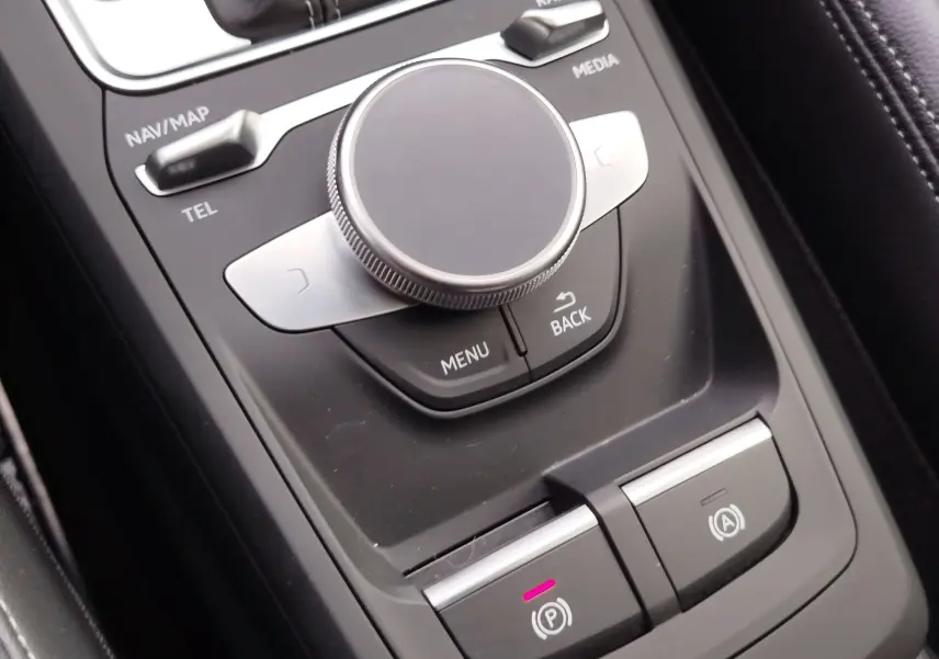 Gros plan sur la molette de commande centrale et les boutons de frein à main électrique dans l'habitacle d'un Audi Q2.