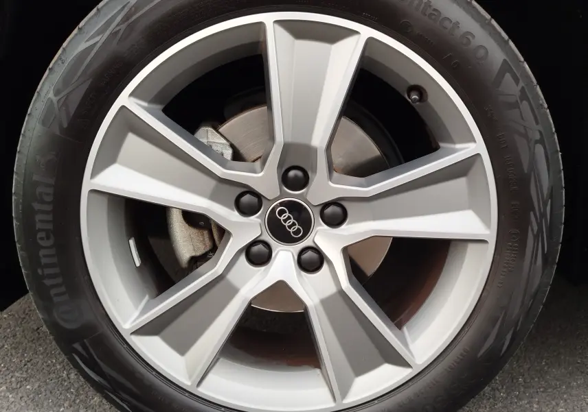 Gros plan sur la jante alliage 18 pouces à cinq doubles branches de l'Audi Q2 bleu Navarre, avec logo Audi central.