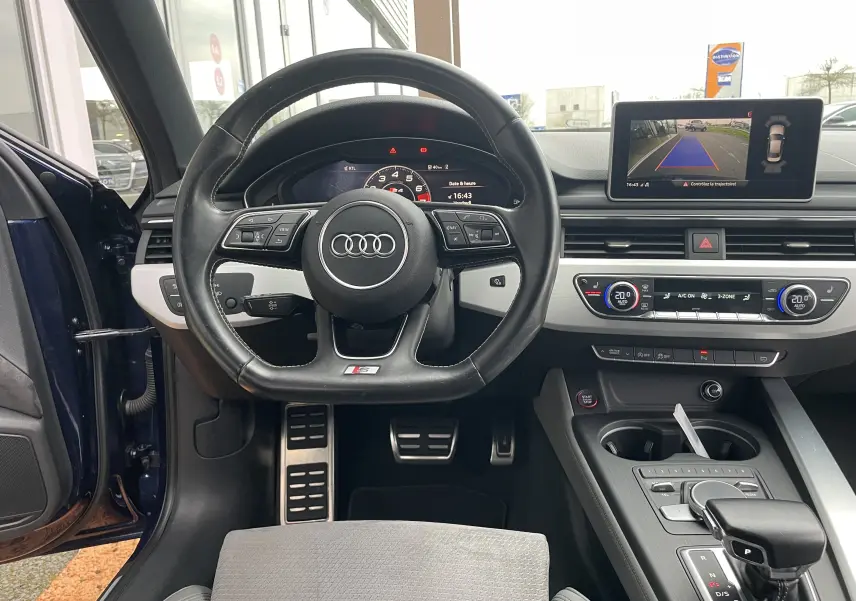 Vue intérieure centrée sur le volant cuir noir et tableau de bord avec écran de recul de l'Audi S4 bleu Navarre 2016.