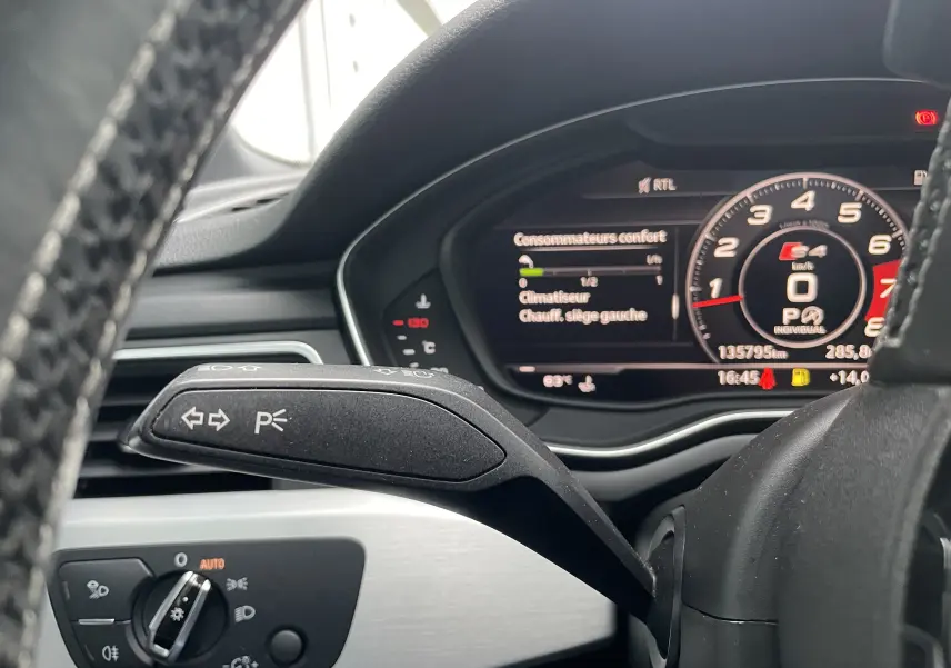 Vue rapprochée du commodo de clignotant à gauche sur le volant d'une Audi S4 2016, tableau de bord numérique en arrière-plan.