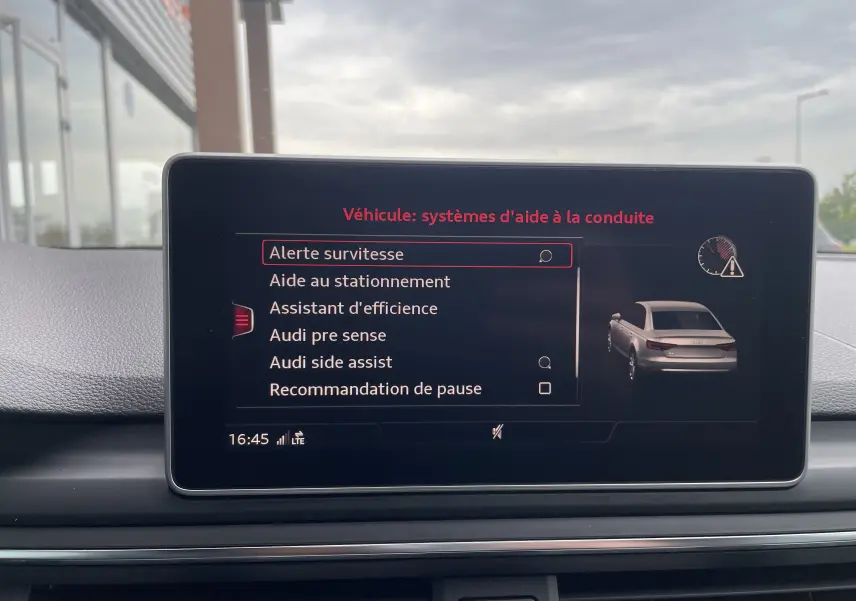 Écran central de l'Audi S4 bleu Navarre affichant les options d'aide à la conduite en intérieur jour.