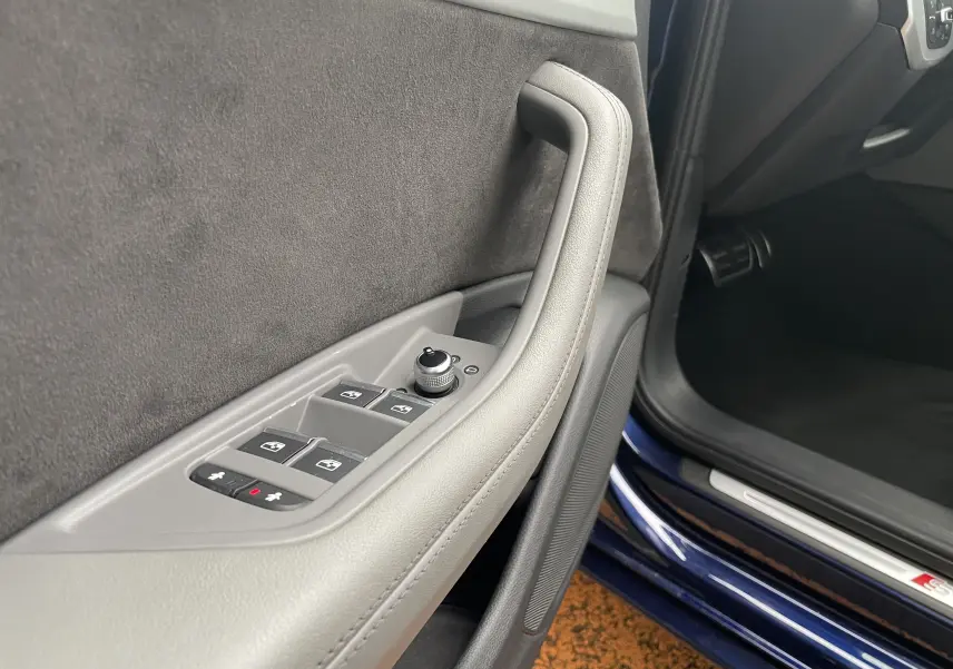 Gros plan sur la porte avant gauche grise de l'Audi S4 2016, avec commandes des vitres et seuil bleu Navarre visible.