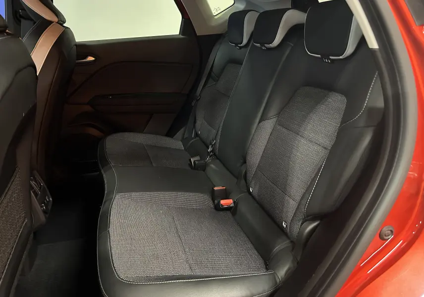 Vue intérieure arrière droite du Renault Captur 2024 rouge flamme métal, sièges arrière en tissu et cuir noir.