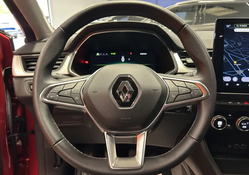 Vue centrée sur le volant du Renault Captur TCE 90CH TECHNO 2024, intérieur noir avec tableau de bord digital et écran tactile.