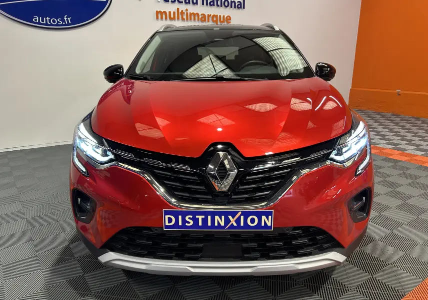 Vue avant d'un Renault Captur 2024 rouge flamme métal avec phares LED allumés et calandre chromée.