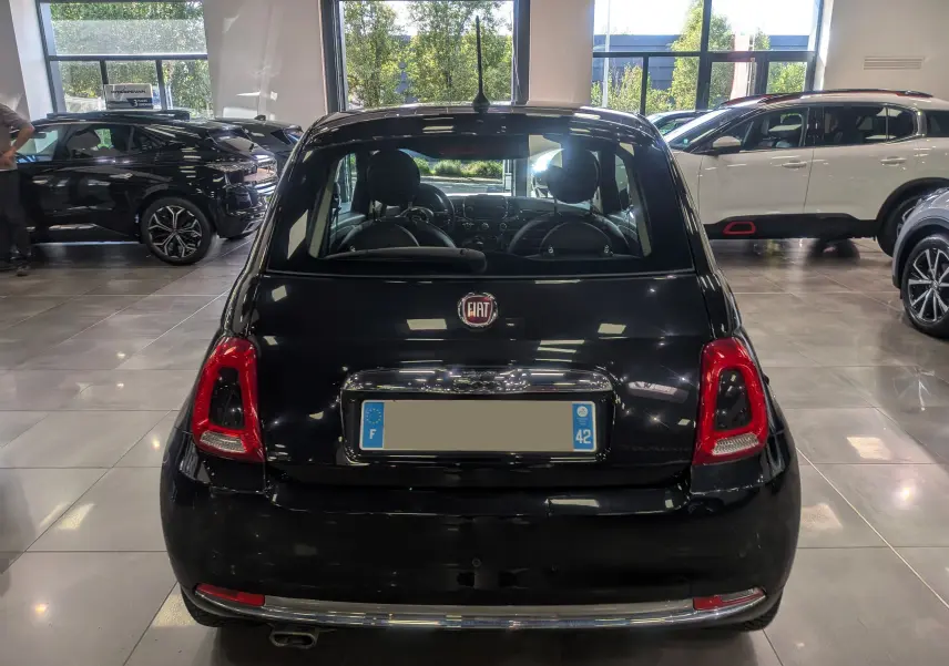 Vue arrière d'une Fiat 500 1.2 69 CH Lounge noire Crossover, stationnée en intérieur avec éclairage naturel.
