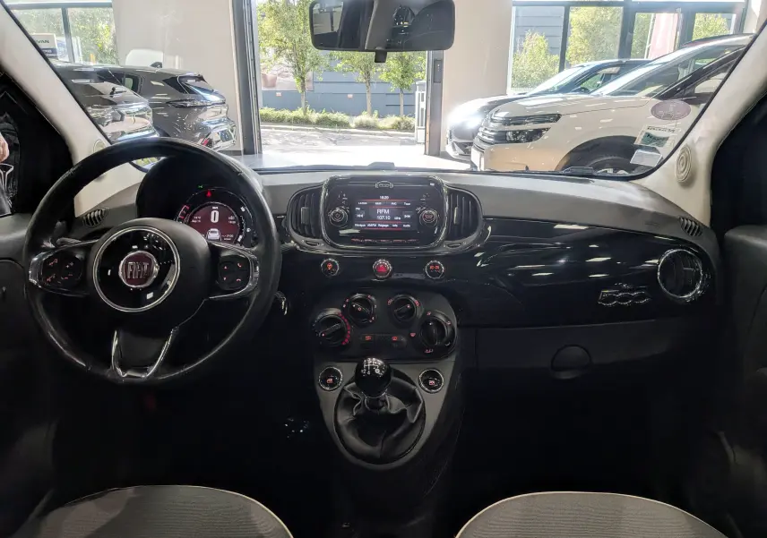 Vue intérieure frontale du tableau de bord noir brillant et volant du Fiat 500 1.2 69 CH Lounge de 2017.
