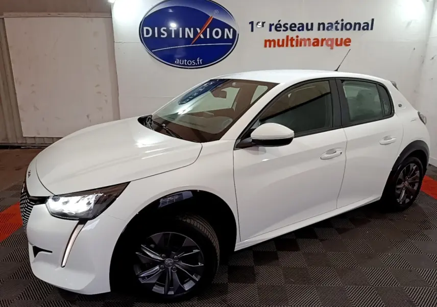 Peugeot 208 électrique Active Business blanc vue 3/4 avant droit avec phares LED allumés en intérieur showroom.