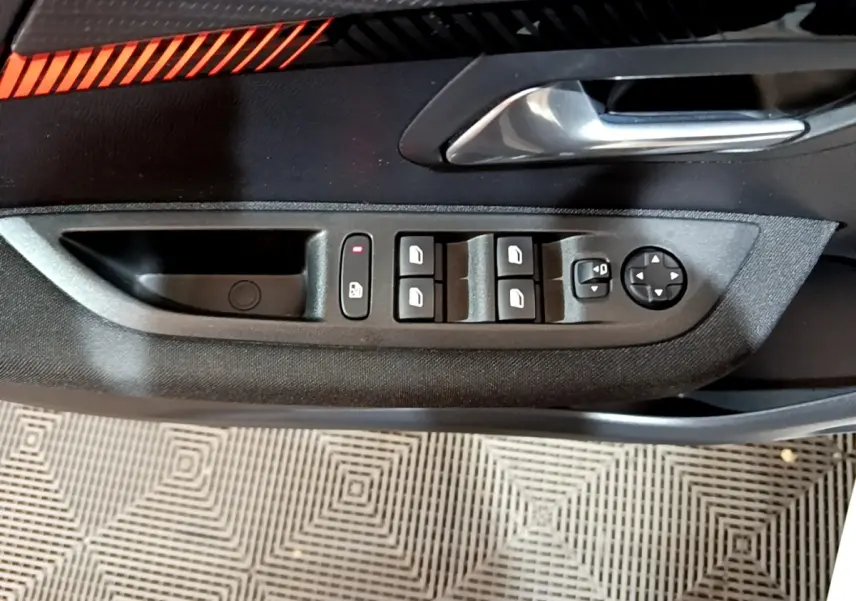 Gros plan sur la commande des vitres et rétroviseurs côté conducteur de la Peugeot 208 électrique blanche Active Business.