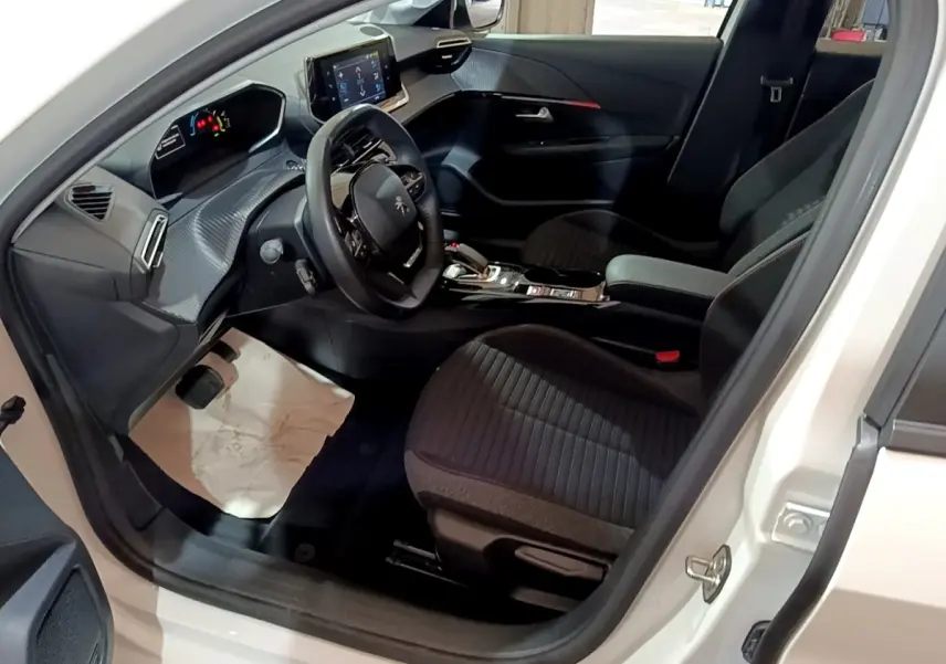Intérieur avant droit d'une Peugeot 208 électrique blanche 2021, tableau de bord moderne avec écran tactile central.