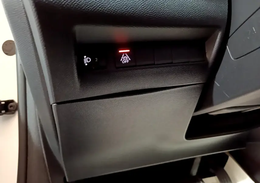 Gros plan sur les commandes noires sous le tableau de bord côté gauche d'une Peugeot 208 électrique blanche 2021.