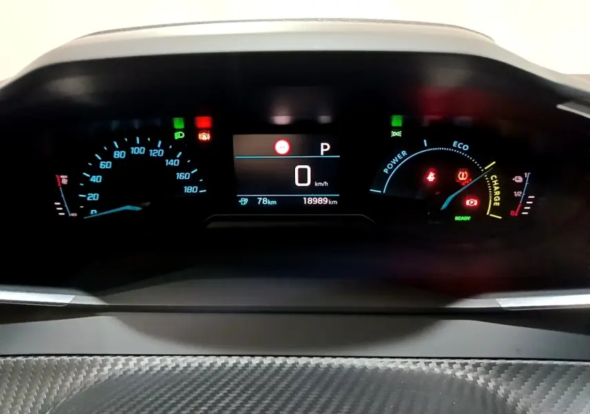 Tableau de bord numérique de la Peugeot 208 électrique blanche, affichant vitesse, autonomie et indicateurs énergie.