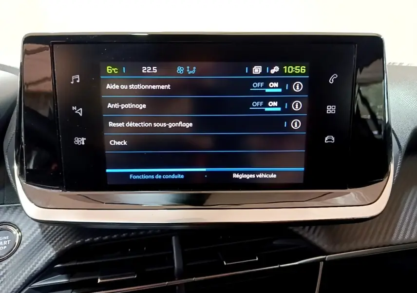 Écran tactile central affichant les réglages d'aide au stationnement et anti-patinage dans une Peugeot 208 blanche électrique.