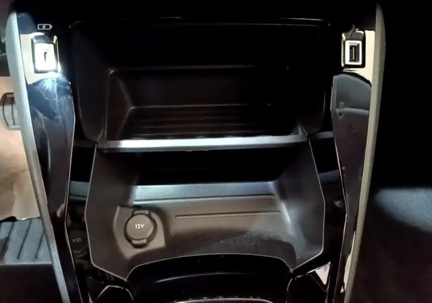 Gros plan sur la console centrale noire du Peugeot 208 Electrique Active Business 2021 avec prise 12V et ports USB.