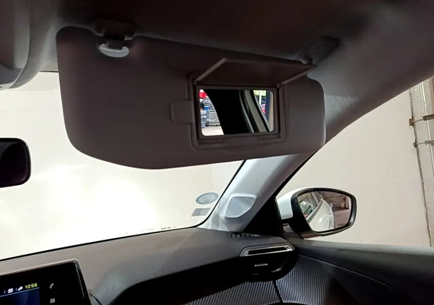 Intérieur de la Peugeot 208 électrique blanche, vue côté passager avec pare-soleil et miroir ouvert.