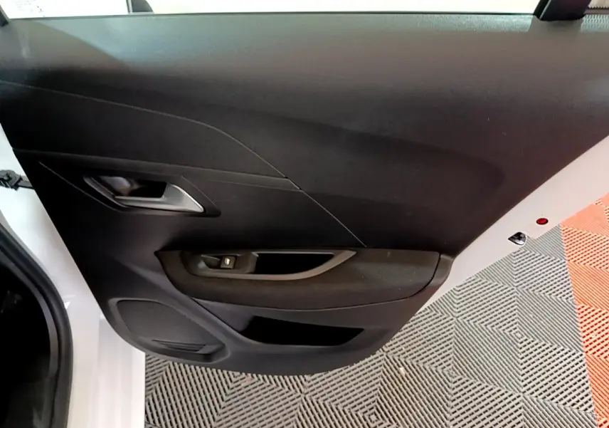 Vue rapprochée de la porte côté gauche blanche du Peugeot 208 Electrique Active Business avec panneau noir et commande de vitre.