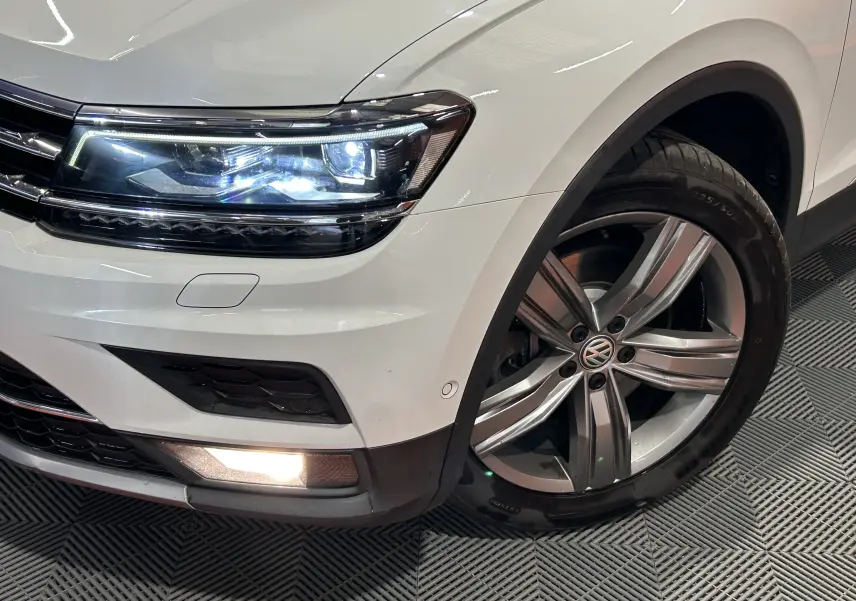 Gros plan sur l'avant droit blanc du Volkswagen Tiguan Allspace 2018 avec phare LED et jante alliage cinq branches.