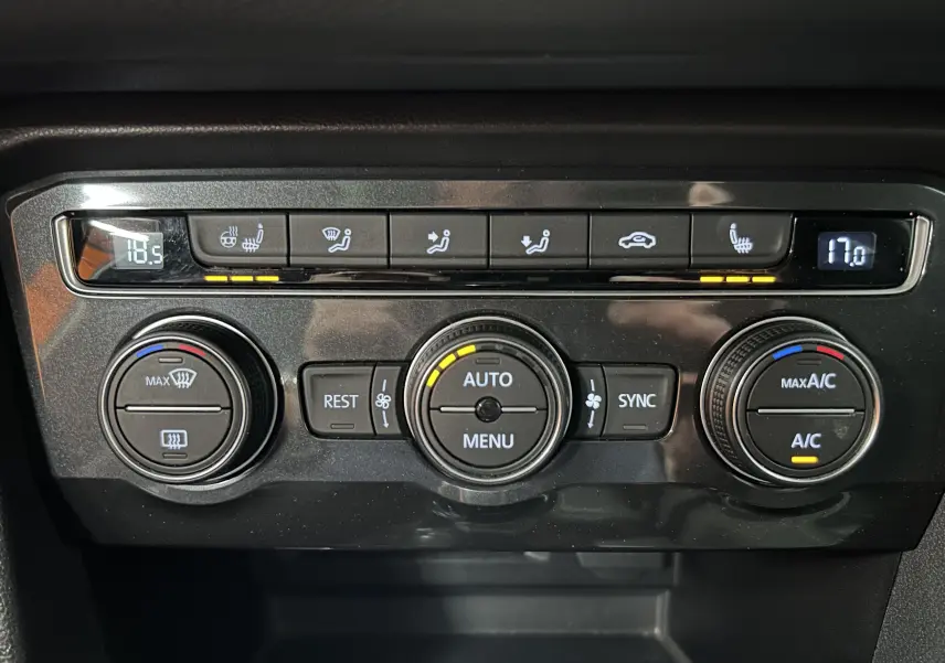 Panneau de commande de climatisation noir du Volkswagen Tiguan Allspace blanc, avec affichage digital et boutons rétroéclairés.