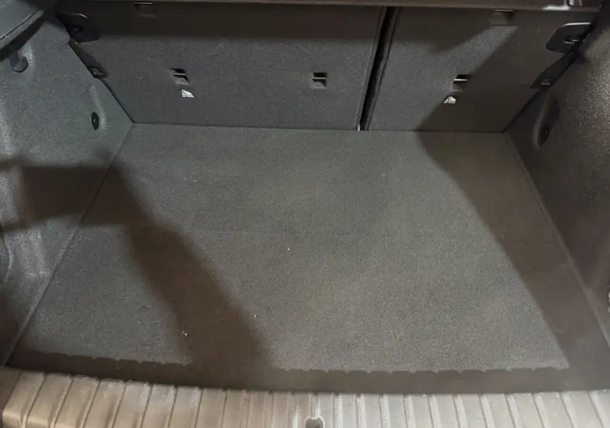 Coffre vide vu de face de la BMW Série 1 116i Business Design 2023, revêtement noir et banquette rabattable.