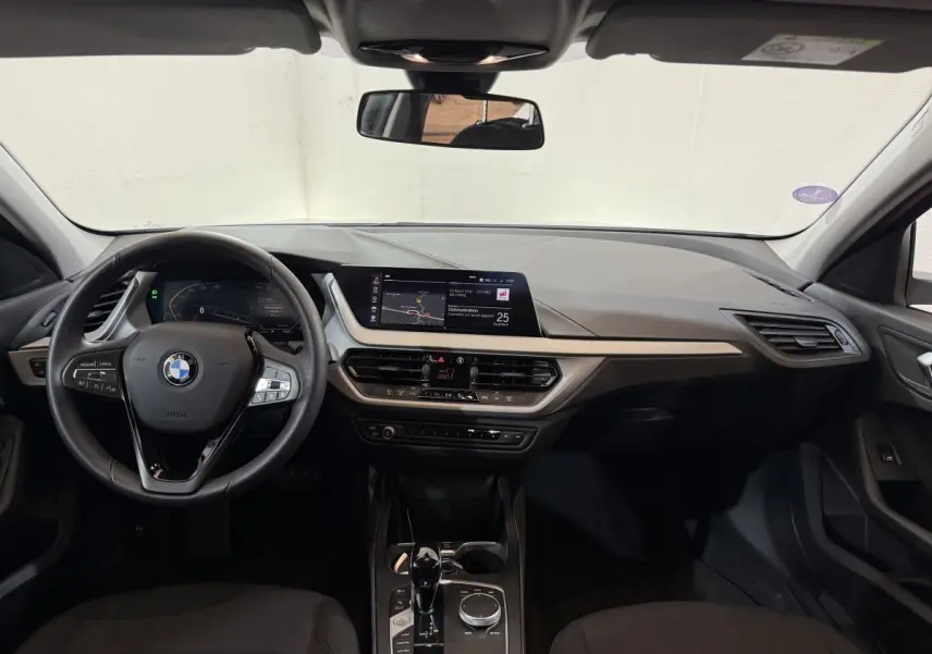 Tableau de bord et volant cuir BMW Série 1 116i 2023 vus de face, avec écran tactile central et commandes modernes.