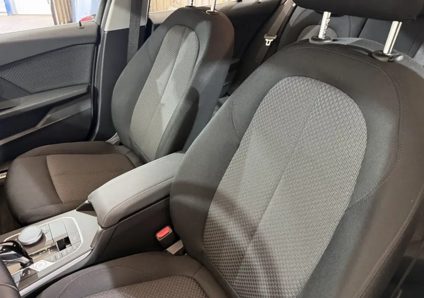 Gros plan sur les sièges avant noirs et gris de la BMW Série 1 116i Business Design 2023, avec console centrale visible.