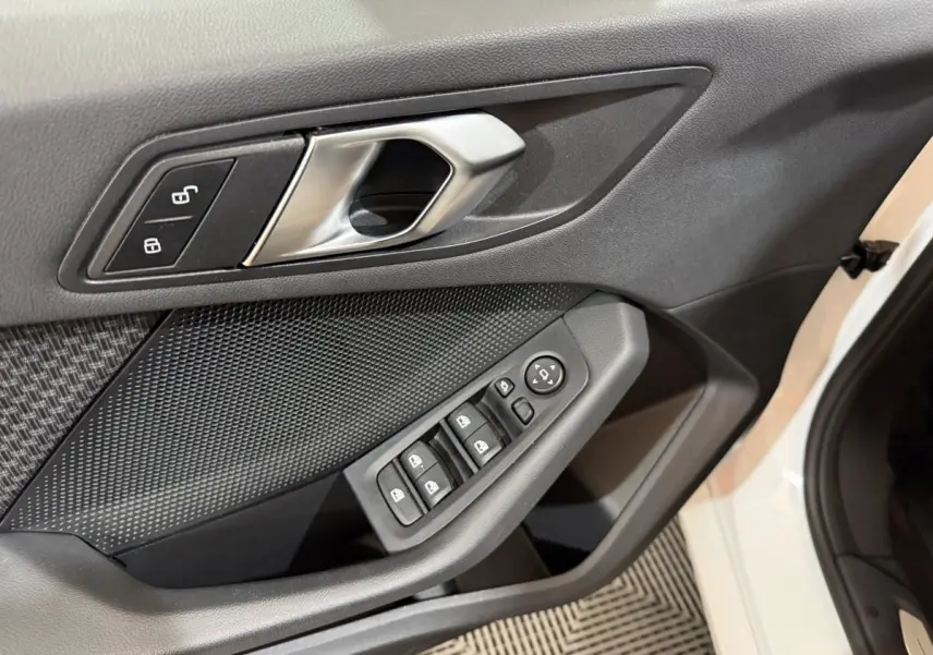 Gros plan sur la porte avant gauche blanche d'une BMW Série 1 116i avec commandes de vitres et poignée métal.