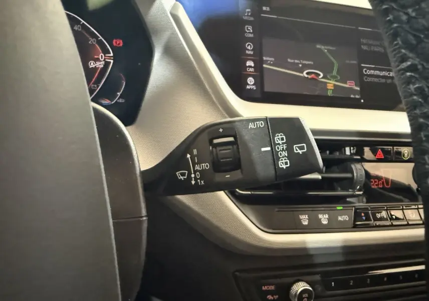 Gros plan sur la commande des essuie-glaces à gauche du volant dans l'habitacle d'une BMW Série 1 blanche 2023.