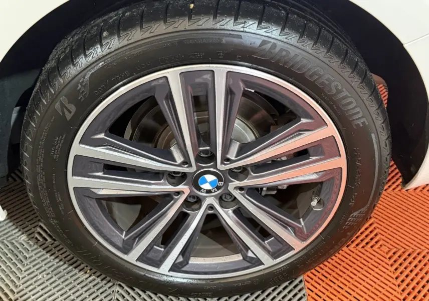 Gros plan sur la jante alliage BMW de la Série 1 blanche, mettant en valeur le pneu Bridgestone et le logo central.