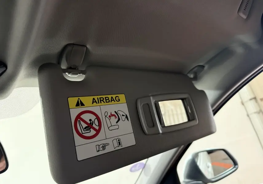 Détail du pare-soleil côté conducteur avec miroir et avertissement airbag dans une BMW Série 1 blanche 2023.