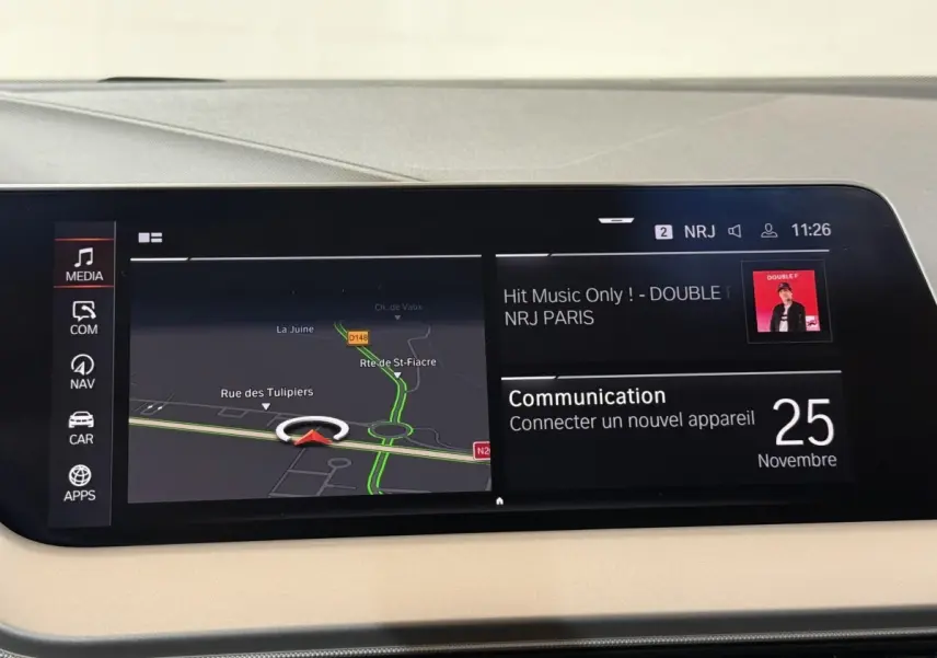 Écran tactile central de la BMW Série 1 116i blanc, affichant navigation et communication, intérieur beige.