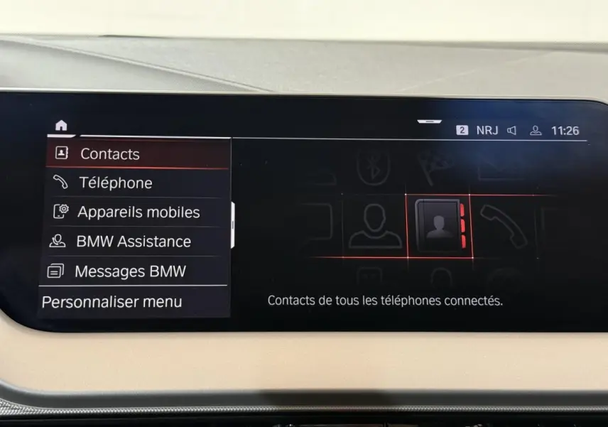 Écran tactile central de la BMW Série 1 blanche 116i DKG7 Business Design affichant le menu contacts.