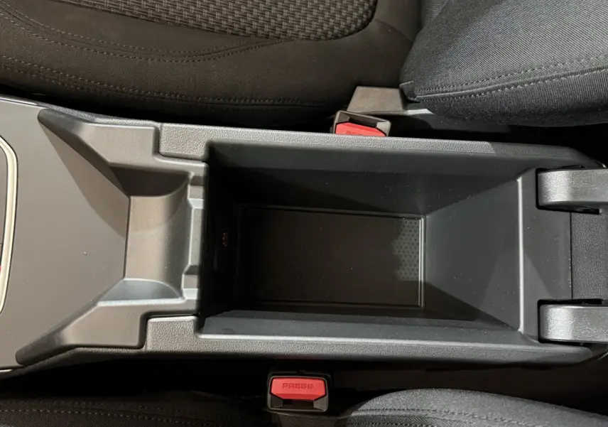 Vue plongeante sur le rangement central noir entre les sièges avant d'une BMW Série 1 116i Business Design 2023.