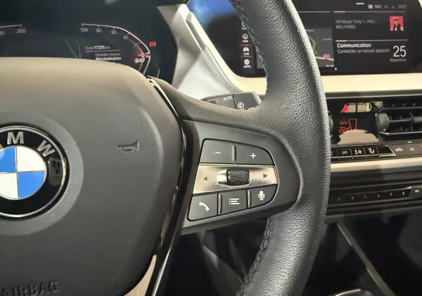 Vue rapprochée du volant cuir multifonctions et du tableau de bord numérique de la BMW Série 1 blanche 2023.