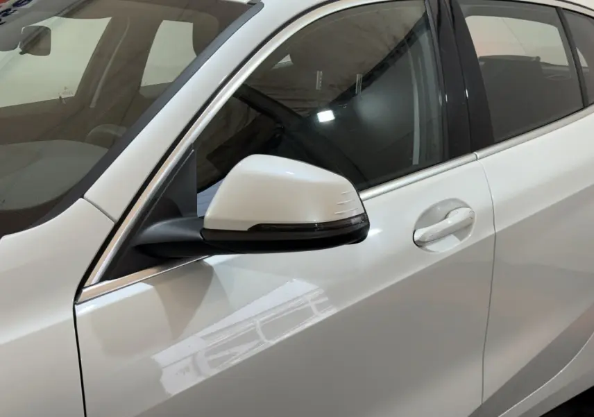 Gros plan sur le rétroviseur côté conducteur blanc de la BMW Série 1 116i DKG7 Business Design 2023.