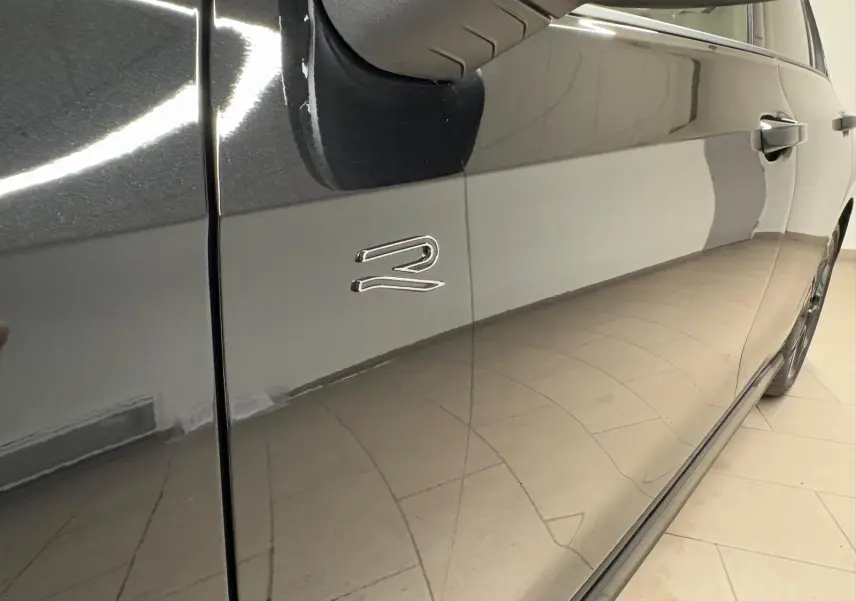 Vue rapprochée du côté gauche d’une Volkswagen Golf 2.0 TDI noire Grenadille avec logo R sur la porte avant.