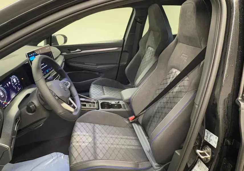 Vue intérieure côté conducteur de la Volkswagen Golf 2.0 TDI R-Line noire, sièges sport avec surpiqûres bleues et volant cuir.