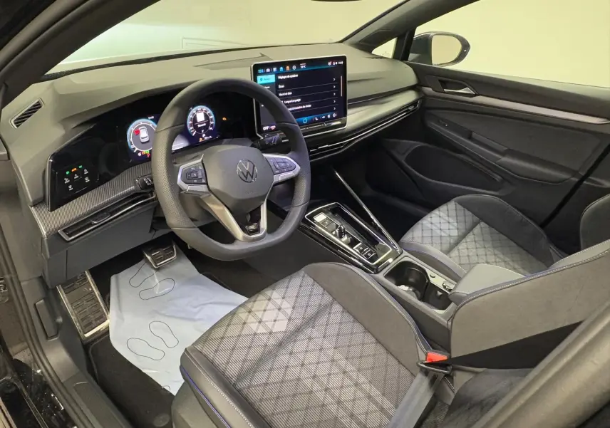 Vue intérieure côté conducteur de la Volkswagen Golf 2.0 TDI 150 DSG7 R-Line avec tableau de bord digital et sièges tissu noir.